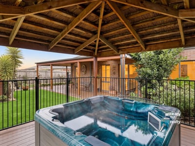 Relax in the inviting hot tub surrounded by lush landscaping and a spacious outdoor retreat.