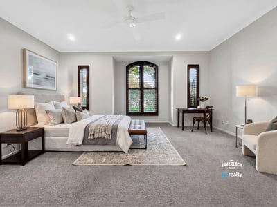 Spacious master bedroom featuring large windows, plush carpeting, and a cozy reading nook.