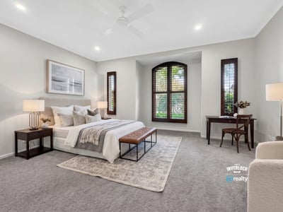 Spacious bedroom featuring large windows, plush carpet, and ample natural light for a cozy atmosphere.