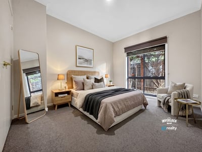 Bright and inviting bedroom featuring large windows, modern decor, and a cozy reading nook for relaxation.