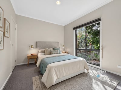 Bright bedroom featuring large windows, cozy furnishings, and a peaceful view of the outdoor greenery.