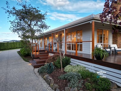 This inviting home features a spacious porch, landscaped gardens, and ample natural light throughout.