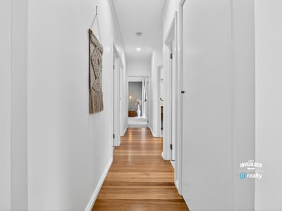 Bright and inviting hallway featuring warm wooden floors and a modern, open layout.