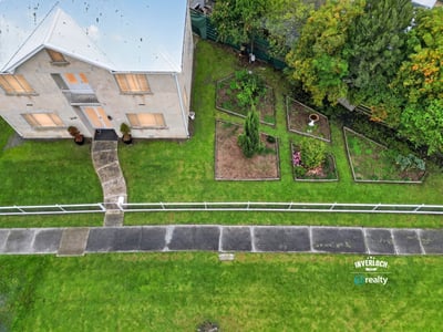 Spacious two-story home with expansive gardens, offering a unique outdoor living experience and plenty of potential.
