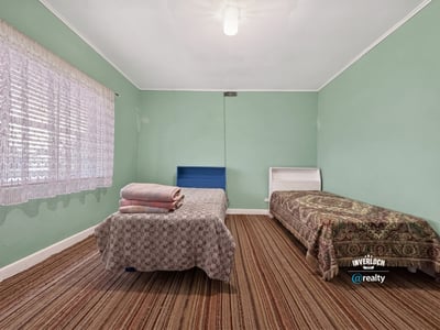 Bright and spacious bedroom with ample natural light, featuring two beds and distinctive patterned accents.