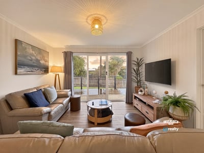 Bright living room with modern furnishings, large window views, and seamless access to an outdoor deck.