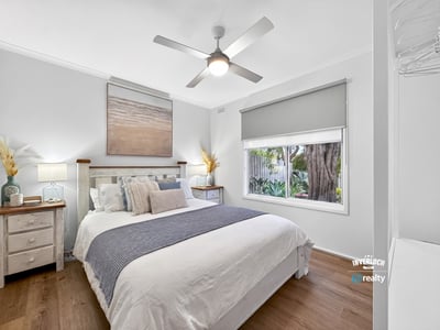 Bright, airy bedroom featuring natural light, modern decor, and a view of lush greenery outside.