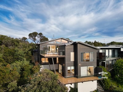 Contemporary home nestled in nature, featuring expansive decks and large windows that invite abundant natural light.