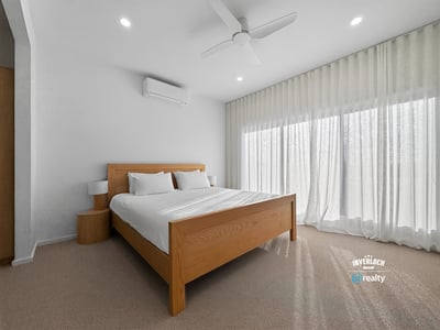 Bright and airy bedroom featuring large windows, modern furnishings, and ample natural light.