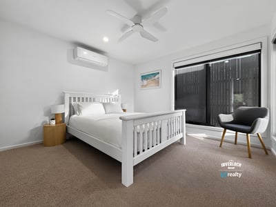 Bright and airy bedroom featuring large windows, modern furnishings, and a cozy atmosphere for relaxation.