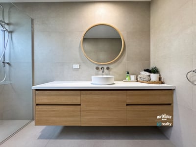 Discover a modern bathroom featuring sleek cabinetry, a striking round mirror, and contemporary fixtures.
