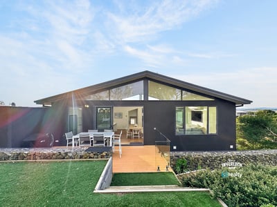 Contemporary home featuring expansive windows and a spacious outdoor deck, perfect for entertaining and relaxation.
