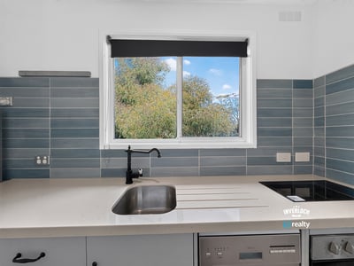 Modern kitchen featuring sleek countertops and a large window that offers refreshing garden views.