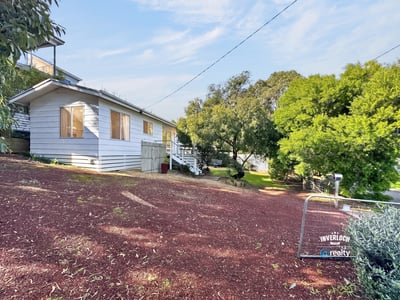 Bright, inviting home on a hillside lot, featuring expansive outdoor space and potential for personalization.