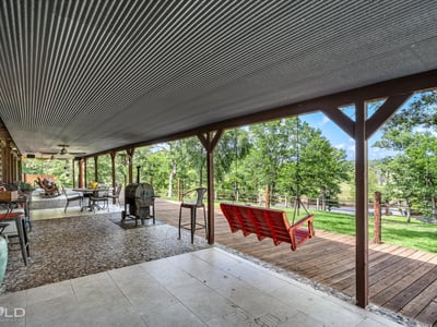 Spacious covered porch offers panoramic nature views, perfect for outdoor gatherings and relaxation.
