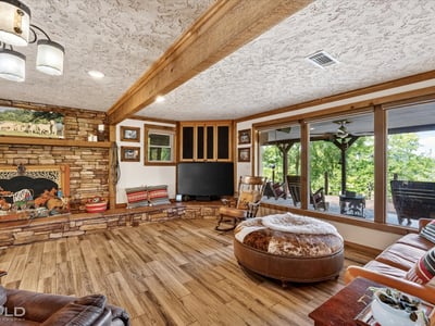 Spacious living area features wood accents and large windows overlooking a picturesque outdoor landscape.