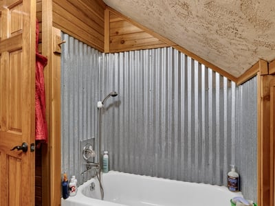 Cozy bathroom featuring a unique corrugated metal accent wall and a comfortable tub for relaxation.