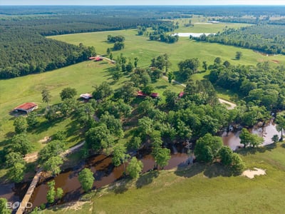 Expansive rural property with lush greenery, waterways, and multiple outbuildings, ideal for diverse development opportunities.