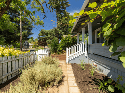 Welcoming entryway lined with lush greenery, leading to a bright and inviting front porch.