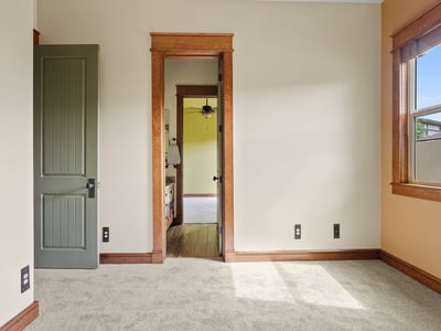 Bright bedroom with soft carpeting, wood-trimmed windows, and classic design elements. A comfortable space filled with natural light and timeless appeal.