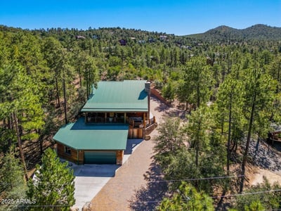 Sweeping aerial photo capturing the home s peaceful forest setting, mature pine trees, and elevated terrain perfect for buyers seeking privacy and scenic surroundings.