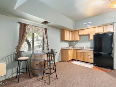 Compact kitchenette with wood cabinetry and dining area, offering added convenience for guests or extended family stays.