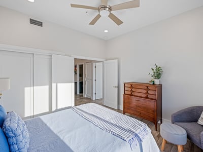 A versatile guest room with neutral tones, wood-look flooring, and bright natural light offers space for family or office use.