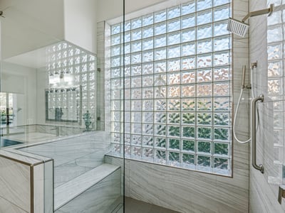 The walk-in shower includes a built-in bench and lighted niche, blending comfort with stylish upgrades.