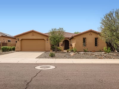 Front elevation with mature trees, desert landscaping, and a two-car garage creates an attractive first impression in this Peoria property.