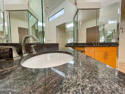 Rich granite countertops and modern hardware bring timeless appeal to this refined bathroom design.