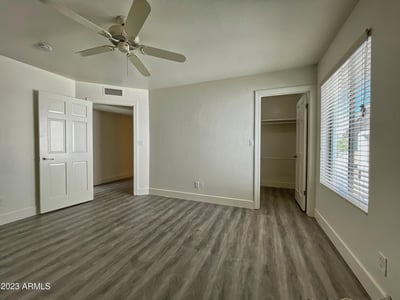 Relaxing bedroom with soft neutral tones, ceiling fan, and ample closet storage, offering comfort and tranquility.
