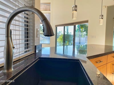 Beautiful granite countertop and stainless faucet positioned to overlook the pool and lake views through bright, open windows.