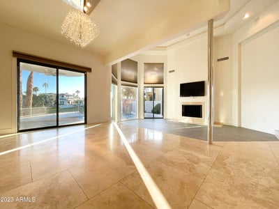 Beautifully designed living room with abundant sunlight, crystal chandelier, and sliding glass doors leading to the lakefront patio.