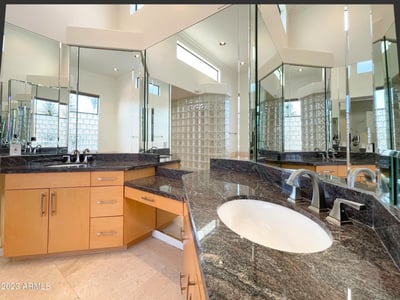 Modern bath design with granite countertops, high-end fixtures, and surrounding mirrors that amplify light and sophistication.