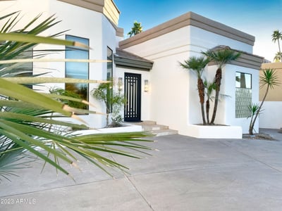 Sleek architectural entry framed by mature palms and desert plants. A stylish welcome to this luxury Scottsdale home.