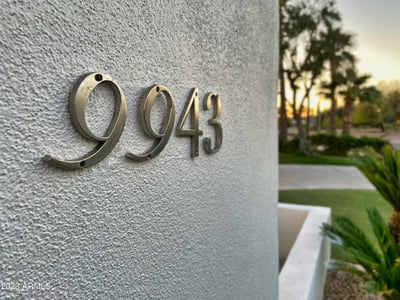 Polished metal address numbers accentuate the sleek stucco exterior, blending modern style with simplicity.