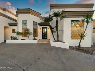Vibrant front yard featuring lush greenery and sculpted palms perfectly complements the home s refined exterior.