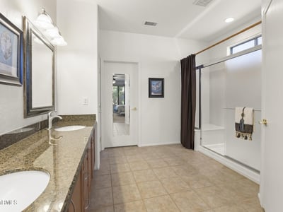 Dual-sink granite vanity and framed mirrors create a polished, spa-inspired space designed for comfort and convenience.