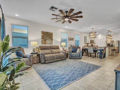 A cozy yet open family room offering modern lighting, comfortable seating, and a seamless connection to the dining area in this Litchfield Park home.