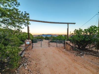 A classic double gate welcomes you to the property, framed by desert foliage and distant mountain ranges that accentuate its serene rural appeal.