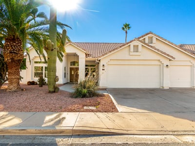 Attractive Scottsdale home exterior surrounded by mature palm trees and native desert landscaping. The well-maintained fa ade, tile roof, and inviting front walkway highlight the home's updated design and strong curb appeal.