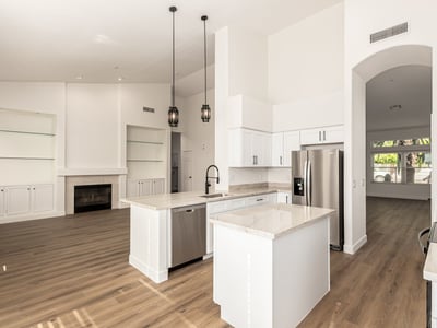Open Scottsdale interior connecting the kitchen and living room with vaulted ceilings and modern flooring throughout. Built-in shelving and a fireplace create a warm focal point for everyday living.