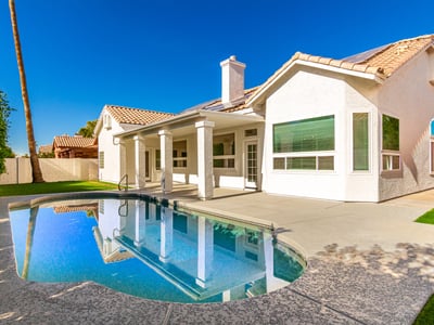 Inviting Scottsdale backyard featuring a sparkling swimming pool, covered patio, and spacious deck area ideal for outdoor gatherings. The private yard creates a relaxing retreat perfect for enjoying sunny Arizona days.