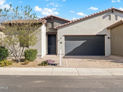 Welcoming exterior presentation with desert landscaping and a paver driveway, offering low-maintenance appeal and modern style in Cave Creek.