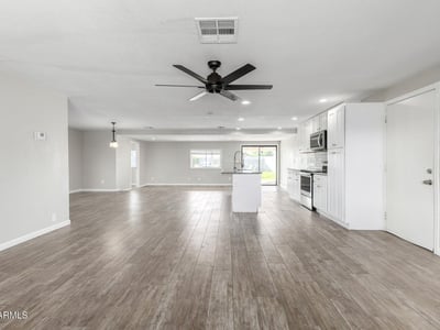 Open-concept great room with recessed lighting, ceiling fan, and wood-look tile flooring offering a bright, airy layout that connects directly to the upgraded kitchen in Phoenix.