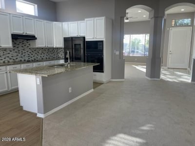 Stylish kitchen featuring granite countertops, upgraded appliances, white cabinetry, and an open layout ideal for daily use and entertaining.