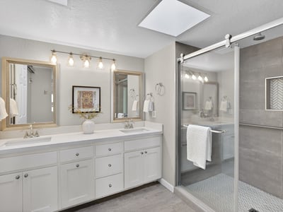 Updated bathroom featuring dual sinks, walk-in shower, modern tile, and stylish fixtures for a spa-like feel.