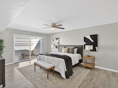 Relaxing primary suite featuring ceiling fan, soft natural light, and direct access to a private courtyard for peaceful mornings.
