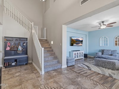 Welcoming entry foyer with soaring ceilings, tile flooring, and staircase leading to the loft and upper living areas of this spacious Queen Creek home.