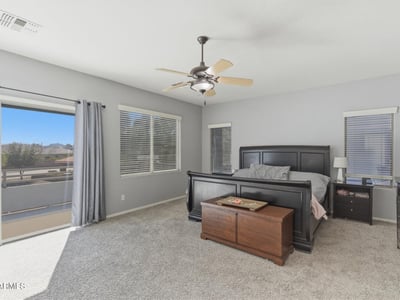 Beautiful primary bedroom with sliding glass doors leading to a private balcony, allowing fresh air and scenic neighborhood views.